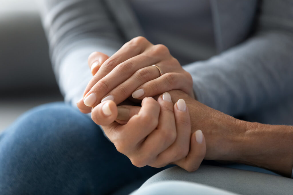 Close up of two people holding hands and supporting eachother